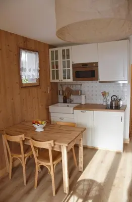 a kitchen with a wooden table and chairs at Chez Colette - Appartement à la montagne in Demi-Quartier