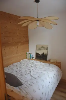 a bedroom with a bed with a ceiling fan at Chez Colette - Appartement à la montagne in Demi-Quartier