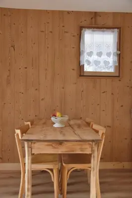a wooden table with chairs and a bowl of fruit on it at Chez Colette - Appartement à la montagne in Demi-Quartier