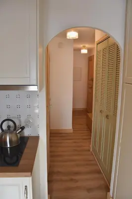 a hallway leading to a kitchen with white cabinets and wood floors at Chez Colette - Appartement à la montagne in Demi-Quartier
