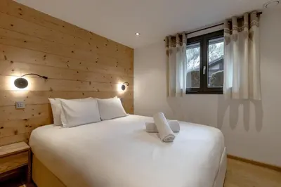 a bedroom with a large white bed with a wooden wall at Jardin du Brevent in Chamonix-Mont-Blanc