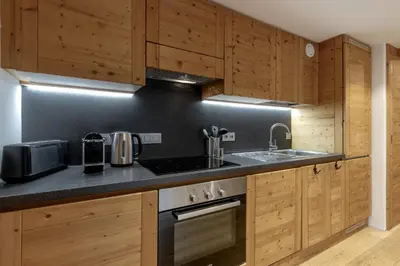 a kitchen with wooden cabinets and a sink and a stove at Jardin du Brevent in Chamonix-Mont-Blanc