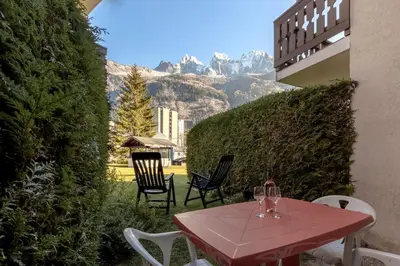 a table and chairs with wine glasses on a patio at Jardin du Mont Blanc in Chamonix-Mont-Blanc