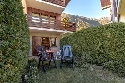 a patio with two chairs and a table in front of a house at Jardin du Mont Blanc in Chamonix-Mont-Blanc