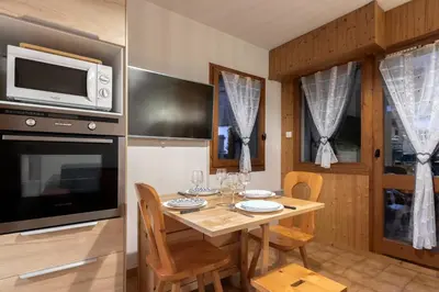 a kitchen with a table with chairs and a microwave at Jardin du Mont Blanc in Chamonix-Mont-Blanc