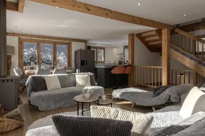 a living room with couches and a kitchen at Chalet Des Grands Vanays in Les Houches