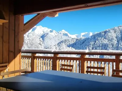 a table on a balcony with a view of snow covered mountains at Chalet Les Pellys - OVO Network in Samoëns