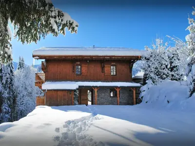a log cabin in the snow with snow covered trees at Chalet Les Pellys - OVO Network in Samoëns