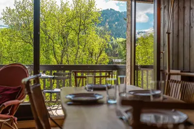 a table with chairs and a view of a balcony at Appartement Cornec - Your stay in Megève in Megève