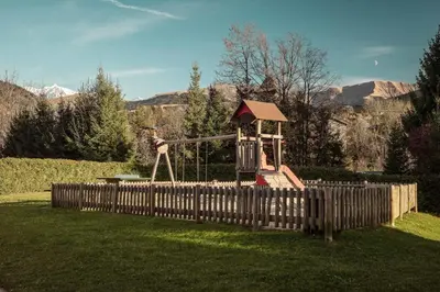 a playground in a yard with a wooden fence at Appartement Cornec - Your stay in Megève in Megève