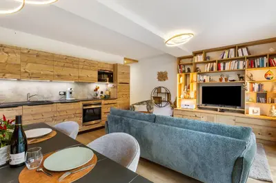 a living room with a blue couch and a television at La Yaute Chamonix-Les Houches in Les Houches