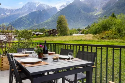 a table on a balcony with a view of mountains at La Yaute Chamonix-Les Houches in Les Houches