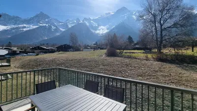 a table and chairs on a balcony with mountains at La Yaute Chamonix-Les Houches in Les Houches