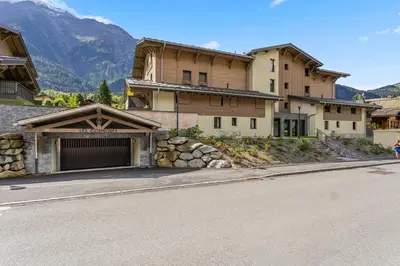 a building with a garage on the side of a street at La Yaute Chamonix-Les Houches in Les Houches