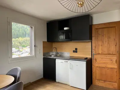 a kitchen with black and white cabinets and a window at Chamonix Charmant duplex 4 personnes et un enfant in Chamonix-Mont-Blanc