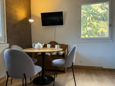 a dining room with a table and chairs and a television at Chamonix Charmant duplex 4 personnes et un enfant in Chamonix-Mont-Blanc
