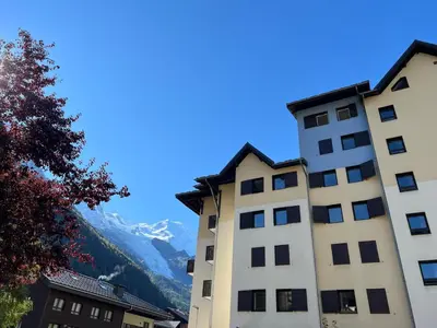 two buildings with mountains in the background at Chamonix Charmant duplex 4 personnes et un enfant in Chamonix-Mont-Blanc