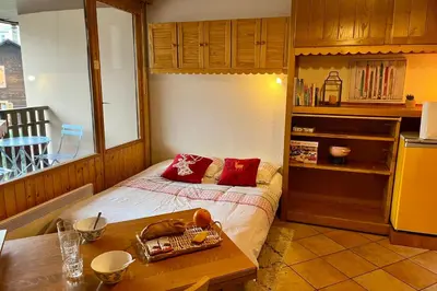 a bedroom with a bed with red pillows and a table at City center studio near the slopes in Chamonix-Mont-Blanc