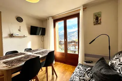 a living room with a table and chairs and a window at Sweetness of the Peaks in Demi-Quartier