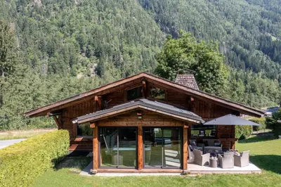 a log cabin with chairs and an umbrella at Chalet Altura- 5 Bedrooms - Jacuzzi and Sauna - By Cozee Rentals in Chamonix-Mont-Blanc