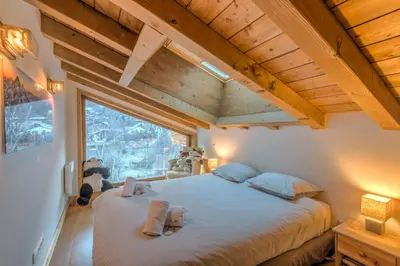 a bedroom with a large bed and a large window at Belvédère du Brévent - Welkeys in Chamonix-Mont-Blanc