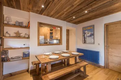 a dining room with a wooden table and a bench at Duplex Megèvan - Welkeys in Megève