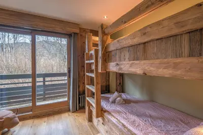 a bedroom with two bunk beds and a window at Duplex Megèvan - Welkeys in Megève