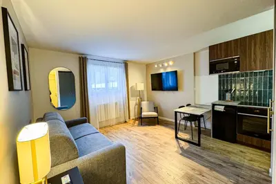 a living room with a blue couch and a kitchen at Beautiful studio close to the slopes in Les Houches