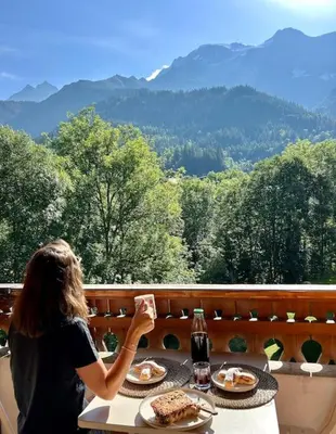 a woman sitting at a table with a plate of food at Appartement avec vue sur les Dômes du Miage in Les Contamines-Montjoie
