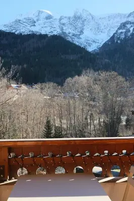 a bench on a balcony with a view of mountains at Appartement avec vue sur les Dômes du Miage in Les Contamines-Montjoie