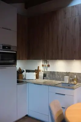 a kitchen with white cabinets and a table in it at Appartement avec vue sur les Dômes du Miage in Les Contamines-Montjoie