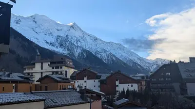 a mountain in the background of a town with houses at Central Mont Blanc View Apartment, balcony, free parking in Chamonix-Mont-Blanc