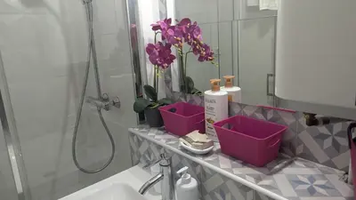 a bathroom with a sink and a mirror and purple flowers at Central Mont Blanc View Apartment, balcony, free parking in Chamonix-Mont-Blanc