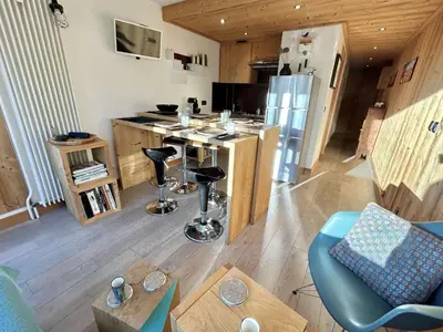 a living room with a kitchen with a counter and a table at Charmant 2 pièces + cabine à Megève, proche remontées et parking inclus - FR-1-597-185 in Megève