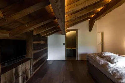 a bedroom with wooden ceilings and a tv and a couch at Chalet de 8 chambres MEGEVE - 16 personnes in Megève