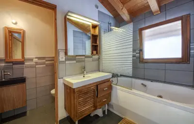 a bathroom with a sink and a tub and a toilet and a window at Chalet Minouche in Chamonix-Mont-Blanc