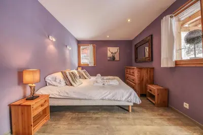 a bedroom with a bed and a purple wall at Chalet Minouche in Chamonix-Mont-Blanc