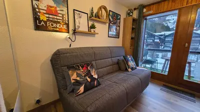 a couch in a living room with a window at Appartement proche télécabine! Séjour tout inclu! in Les Contamines-Montjoie