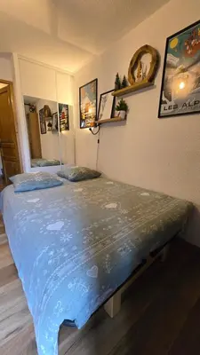 a bedroom with a large bed with a blue comforter at Appartement proche télécabine! Séjour tout inclu! in Les Contamines-Montjoie
