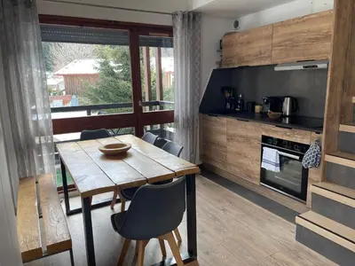 a kitchen with a wooden table and a dining room at Le Marlotte in Les Carroz d'Araches