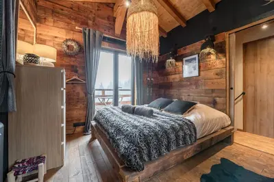 a bedroom with a bed in a room with wooden walls at Chalet ski-in-out face au MontBlanc & Bain nordique in Megève