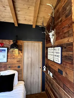 a bedroom with a wooden wall with a deer head on the wall at Chalet ski-in-out face au MontBlanc & Bain nordique in Megève