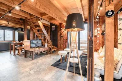 a living room with a staircase and a table at Chalet ski-in-out face au MontBlanc & Bain nordique in Megève