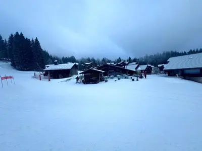 a snow covered field with a group of buildings at Les Esserts au pied des pistes idéal 4 personnes in Morillon