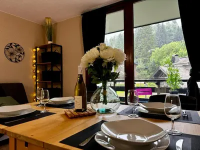 a dining table with a vase of flowers and wine glasses at Les Esserts au pied des pistes idéal 4 personnes in Morillon