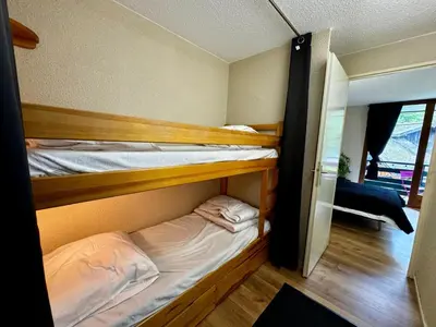 a bedroom with a bed with a blue blanket at Les Esserts au pied des pistes idéal 4 personnes in Morillon