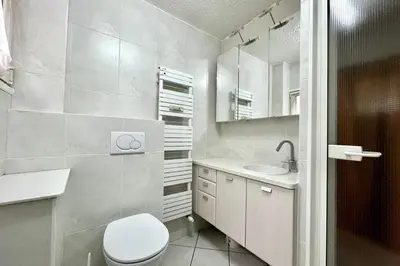 a white bathroom with a toilet and a sink at Apartment 2 rooms near the slopes in Combloux