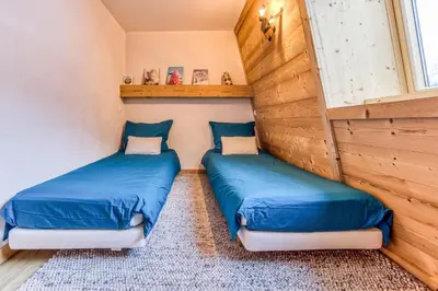 two beds in a room with wooden walls at Apt Le Lyret in Chamonix-Mont-Blanc