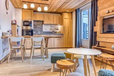 a kitchen with wooden cabinets and a table and chairs at Apt Le Lyret in Chamonix-Mont-Blanc