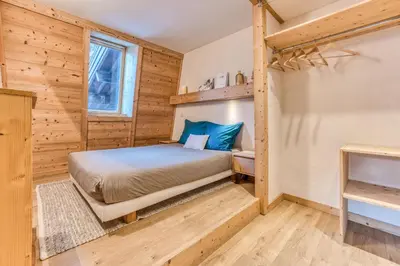a log cabin bedroom with a bed and a window at Apt Le Lyret in Chamonix-Mont-Blanc
